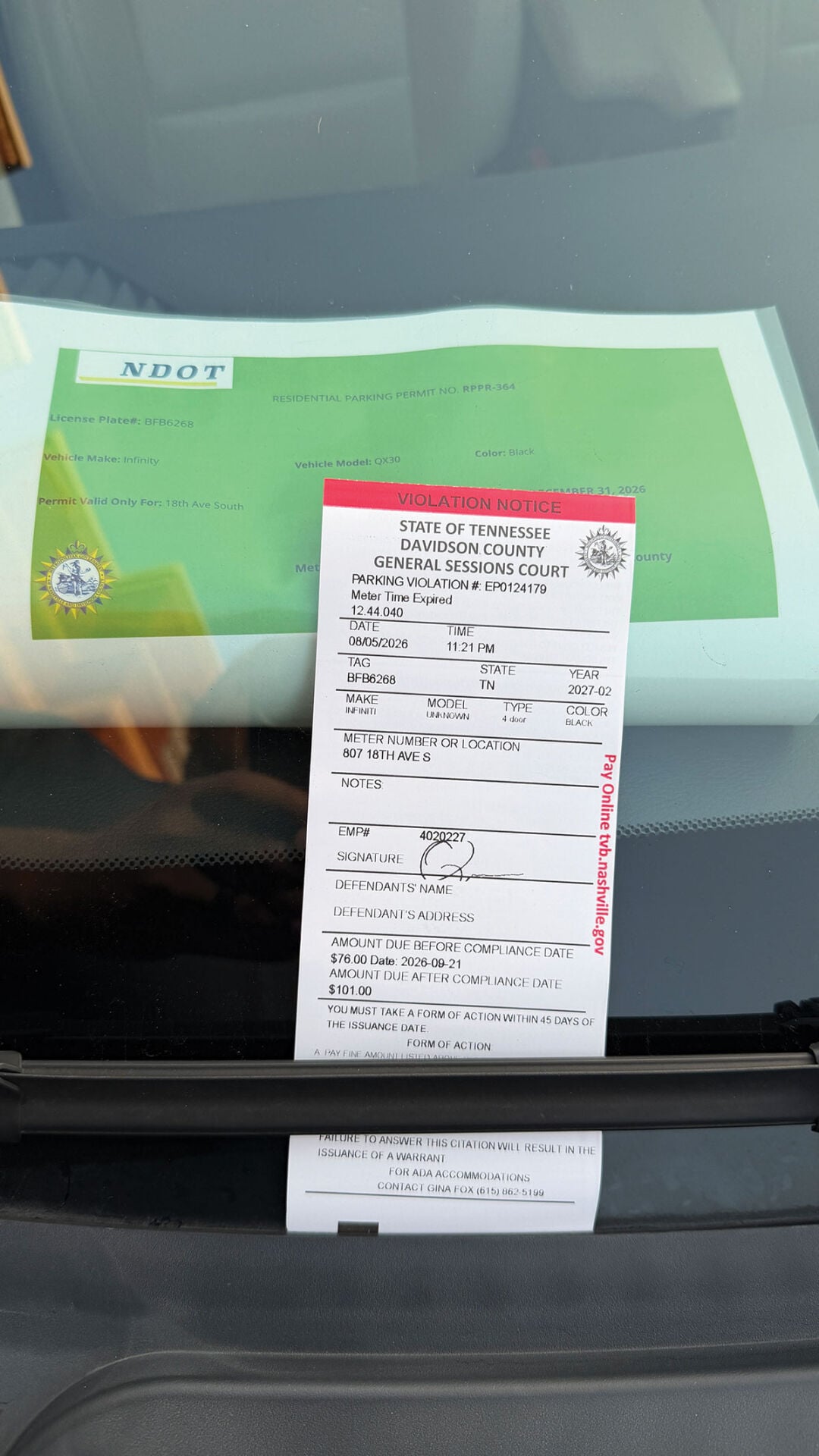 A printed Metro residential parking permit next to the parking ticket issued against it
